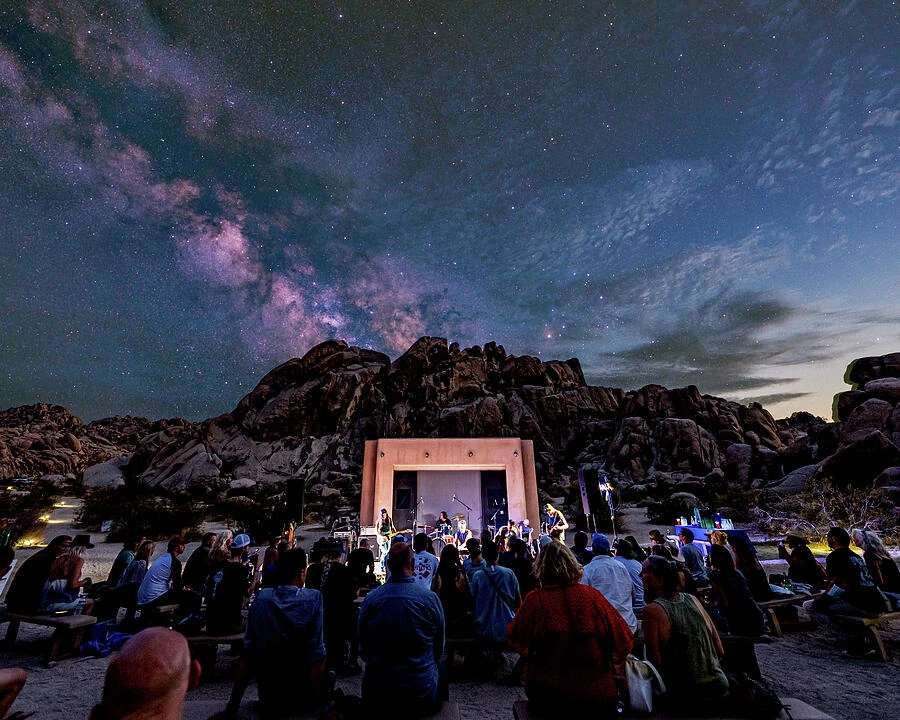 People gathered among Joshua Tree’s rocky terrain beneath the Milky Way.